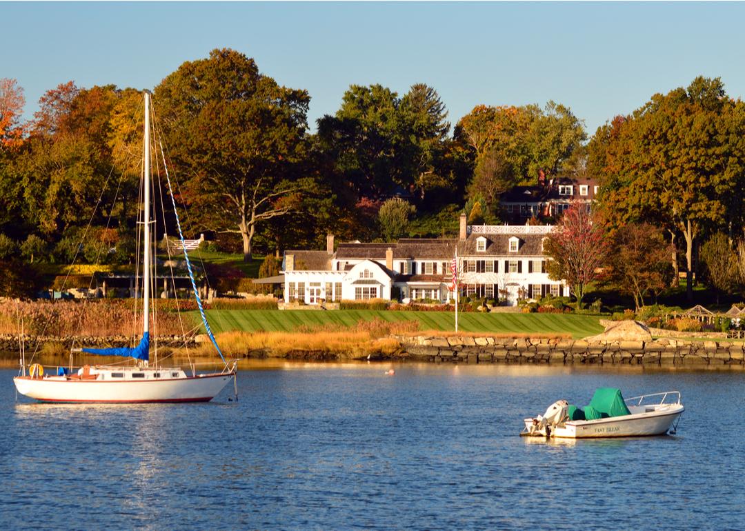 A sailboat moored in front of a luxury waterfront estate in Greenwich.