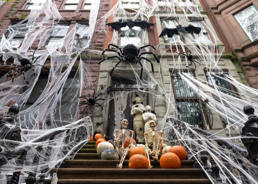 A stoop in NY decorated with pumpkins, spider webs and mummies.