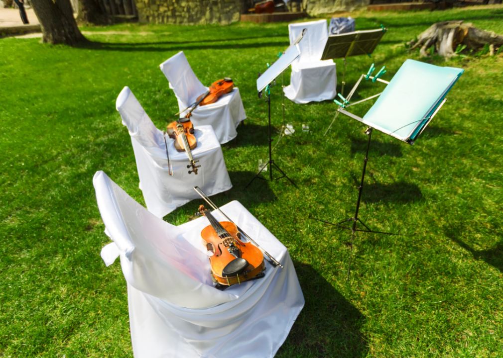 Violins on chairs at an outdoor event.