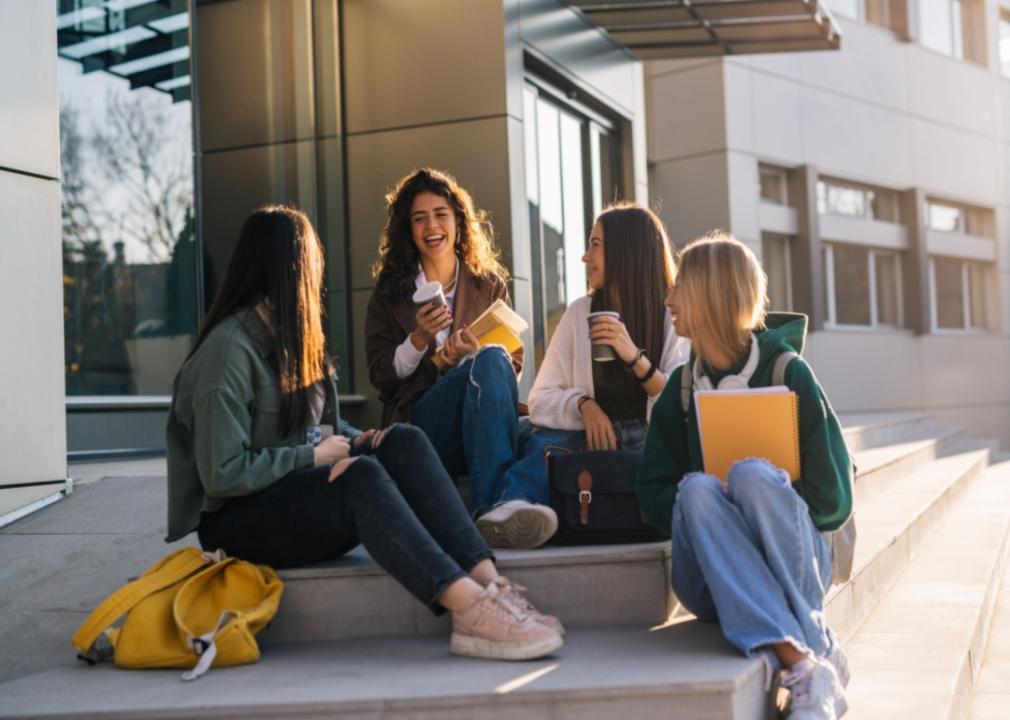 Students laughing while sitting outside on campus.
