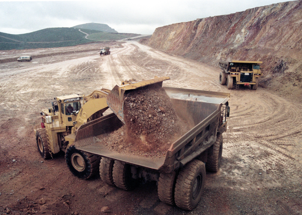 Dump trucks unload mining tailings.