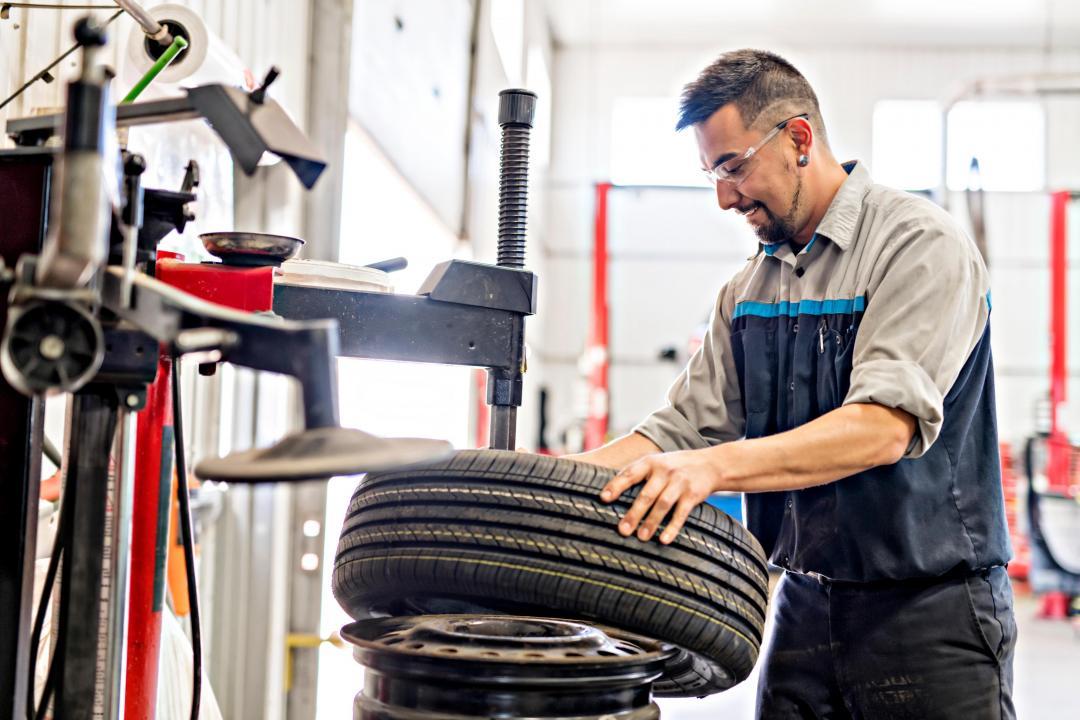A garage worker prepares a new tire.