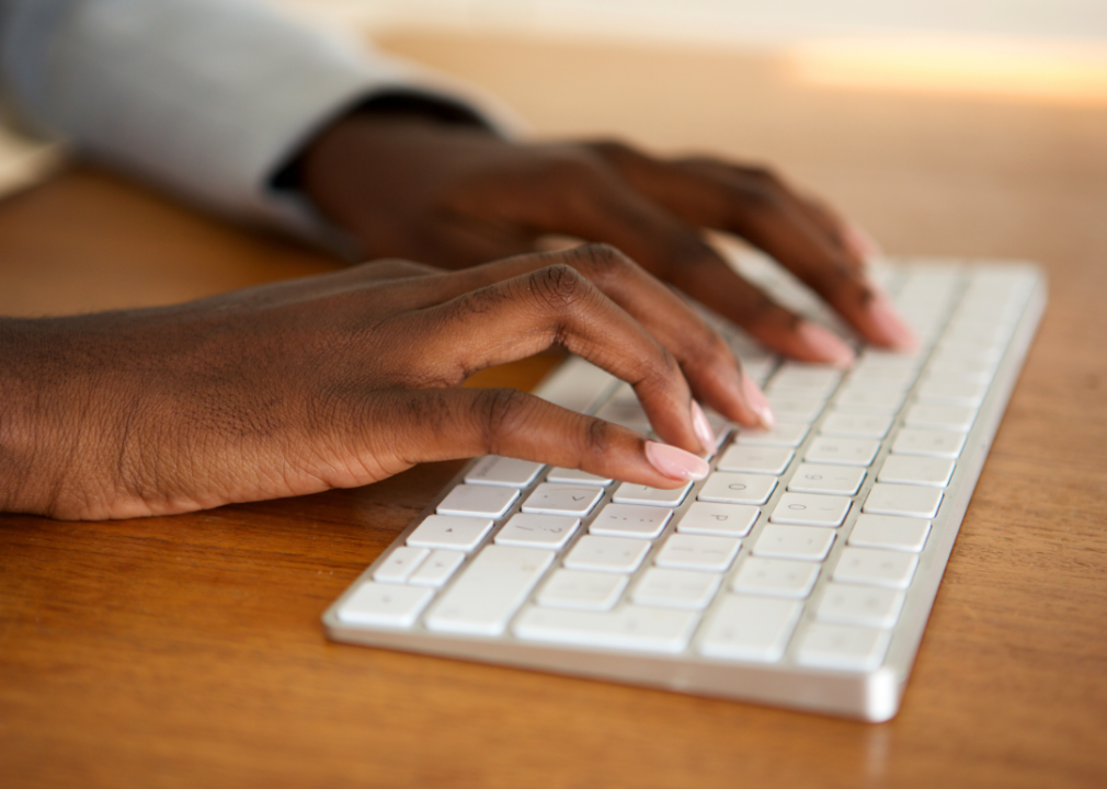 Hands typing on a wireless keyboard.