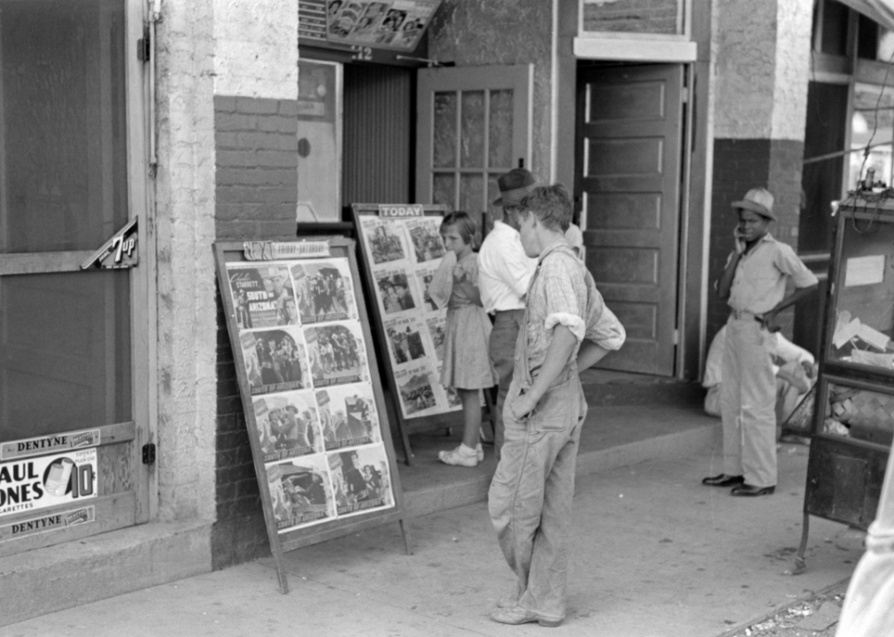 Children looking at posters displayed on a sidewalk in Steele, Missouri 1938. 