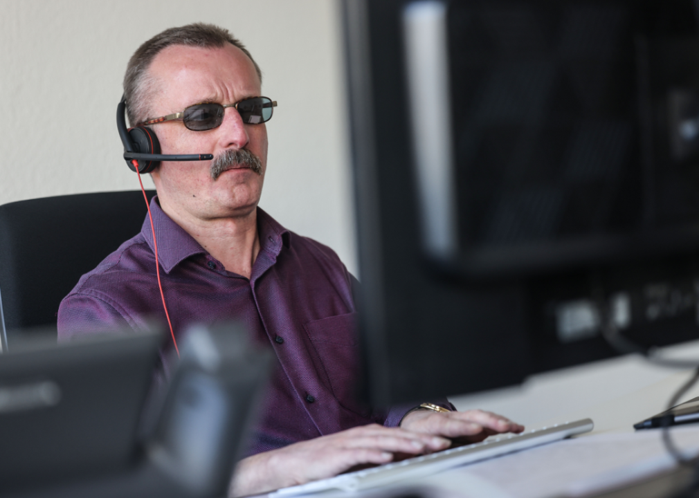 A man with a visual disability wears a headset mic as he uses a computer.