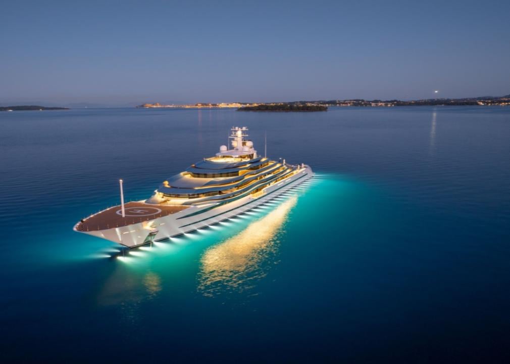 A yacht on the water lit up at night.