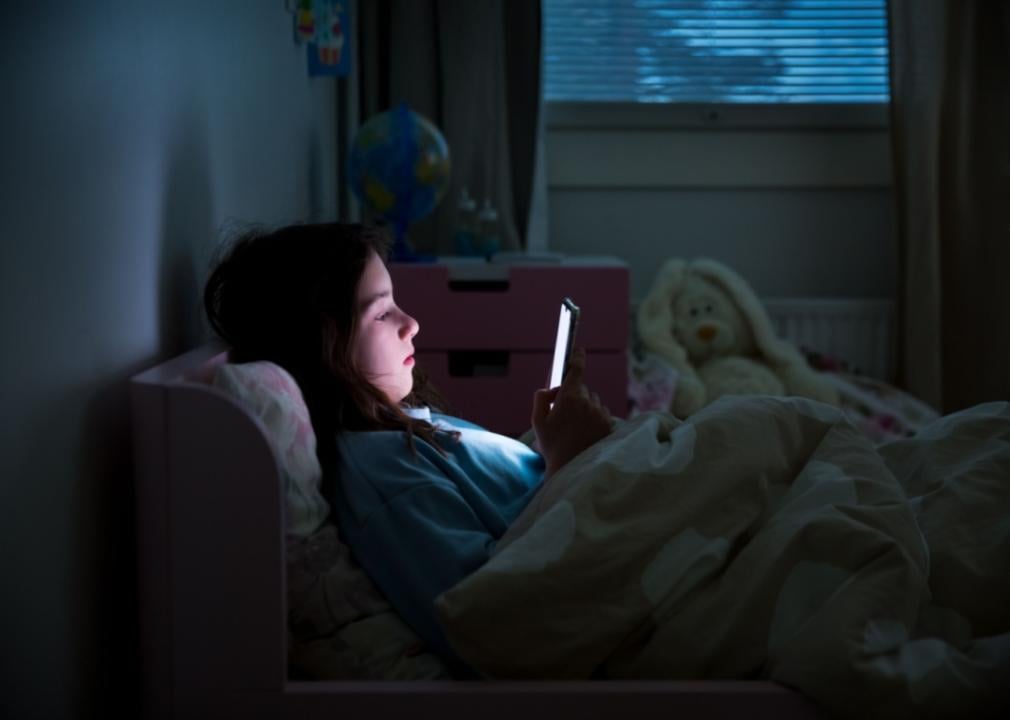 A young girl on her phone in bed.