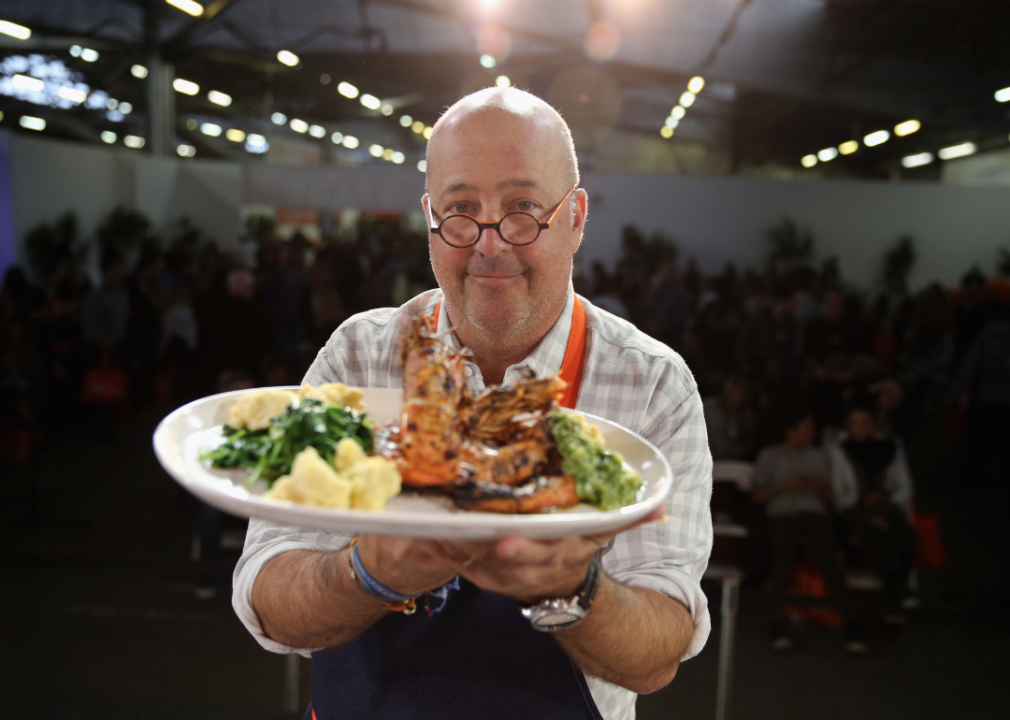 Andrew Zimmern holding a plate of food.