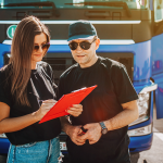 Two truck drivers review clipboard in front of semi truck.