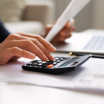 Closeup of hands on calculator paying bills.