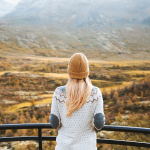 Woman in sweater looking out over dramatic fall landscape.