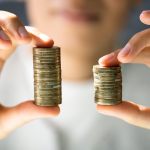 Hands holding unequal stacks of coins.