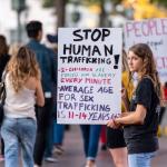 Young adult holding “Stop Human Trafficking” sign at awareness demonstration.