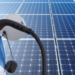 Close up of electric car with a connected charging cable on the background of solar panels.