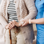 Nurse assisting senior woman with cane.