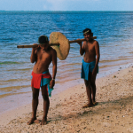 Men carrying an ancient stone coin on Yap Island.