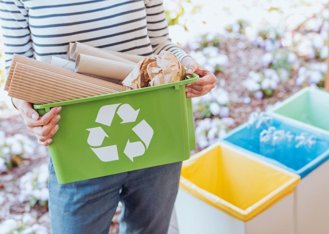 Person holding green recycle bin