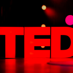 The TED logo illuminated on stage