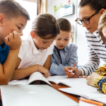 A teacher helps young students with lesson.