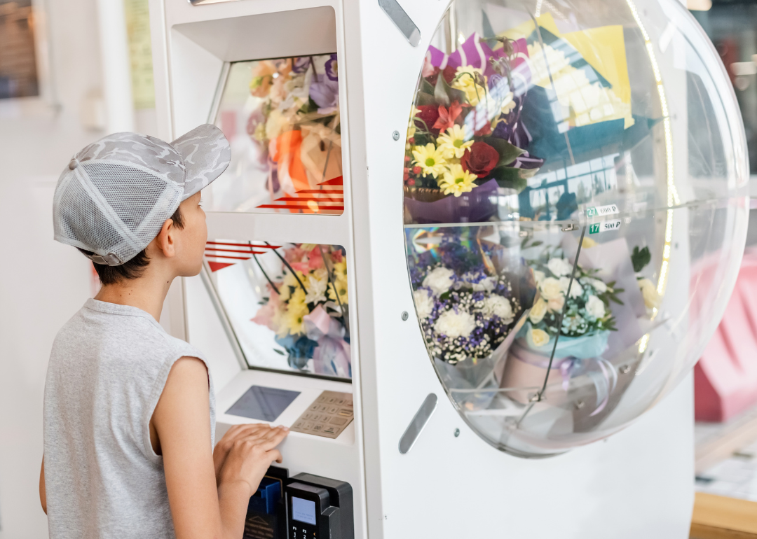 Child purchasing flowers from vending machine.