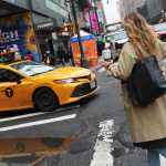 A woman in New York City hails a yellow taxi cab