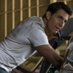 Tom Cruise in a white T-shirt leans into a car in "Top Gun: Maverick"