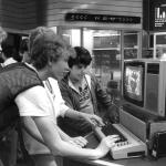 Teens play on a computer in a shopping mall in 1984. 