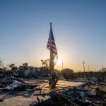 The American and City of New Orleans Mardi Gras flag is seen standing in a field of tornado-damaged wreckage in the Arabi neighborhood on March 24, 2022 in New Orleans, Louisiana.
