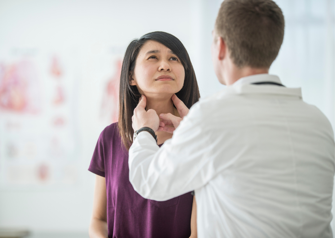Doctor examining woman's thyroid, checking for cancer.