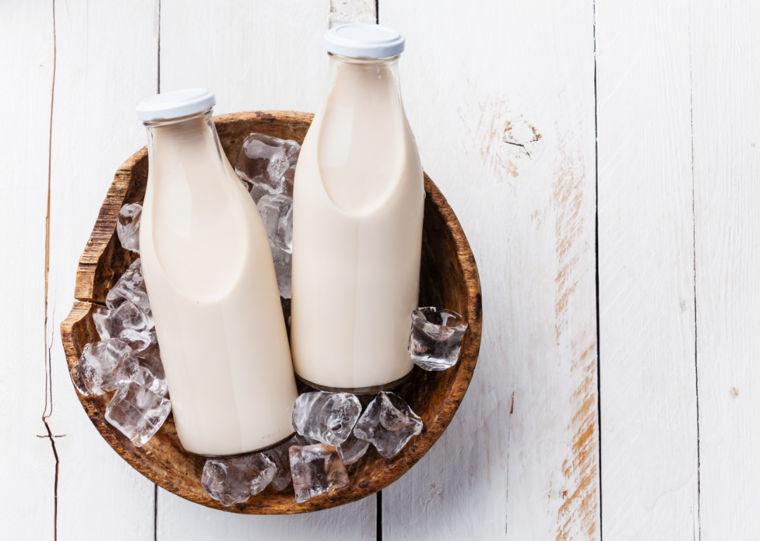 Two milk bottles resting in a wooden bowl