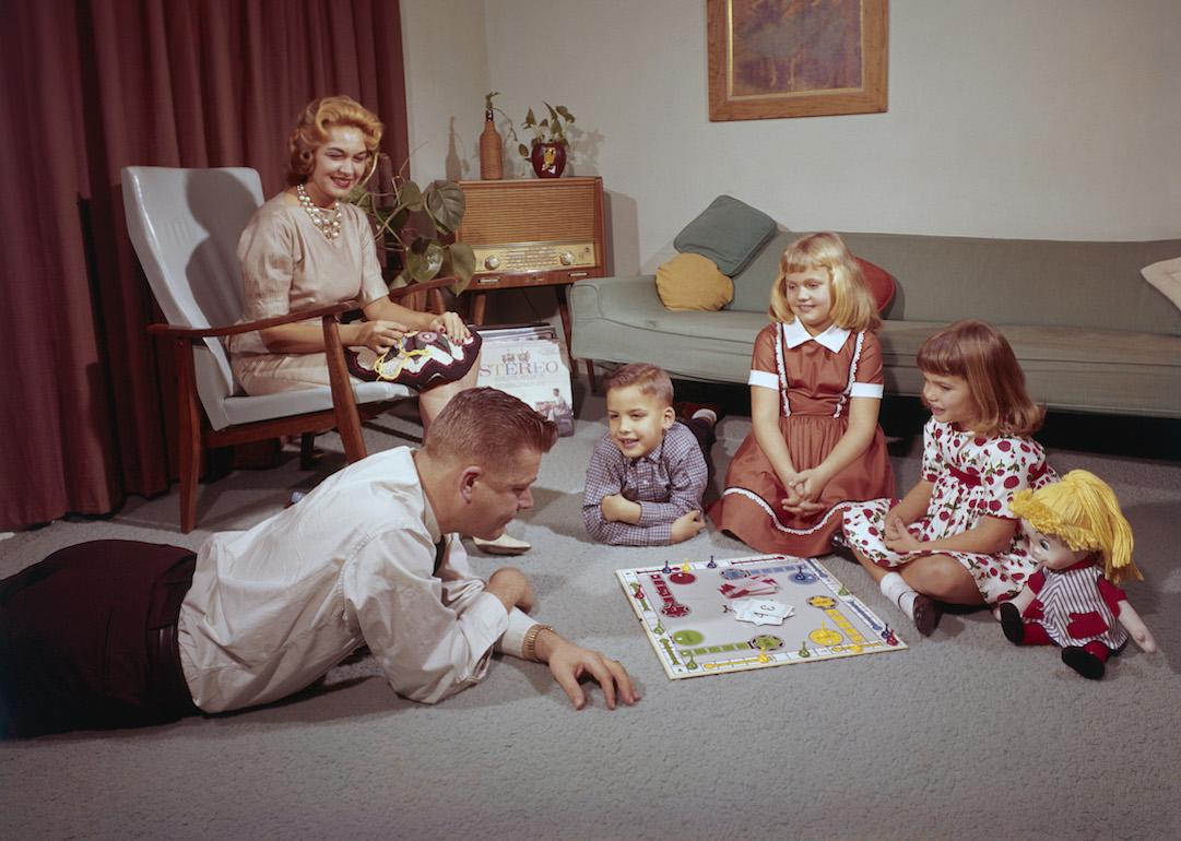 A young family playing a board game with their dad while the mother crochets in 1962.