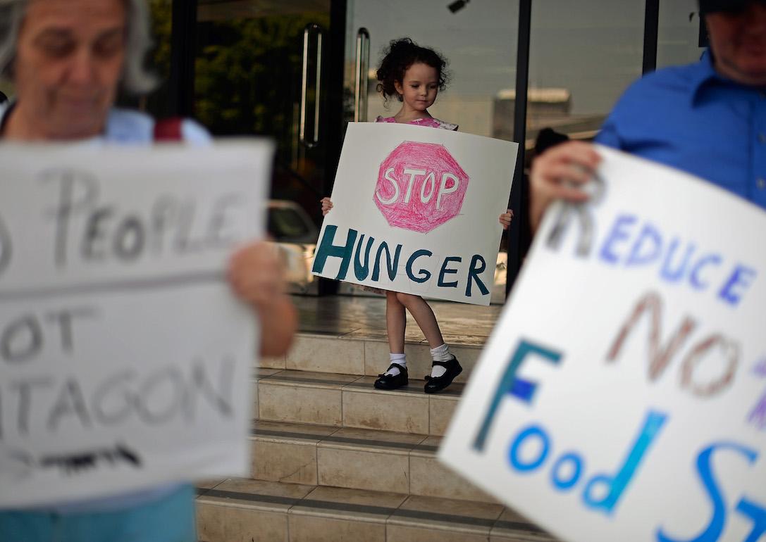 Child holds a sign with other activists as they hold a rally to protestor a House farm bill that would reduce federal spending on the Supplemental Nutritional Assistance Program by $20.5 billion.