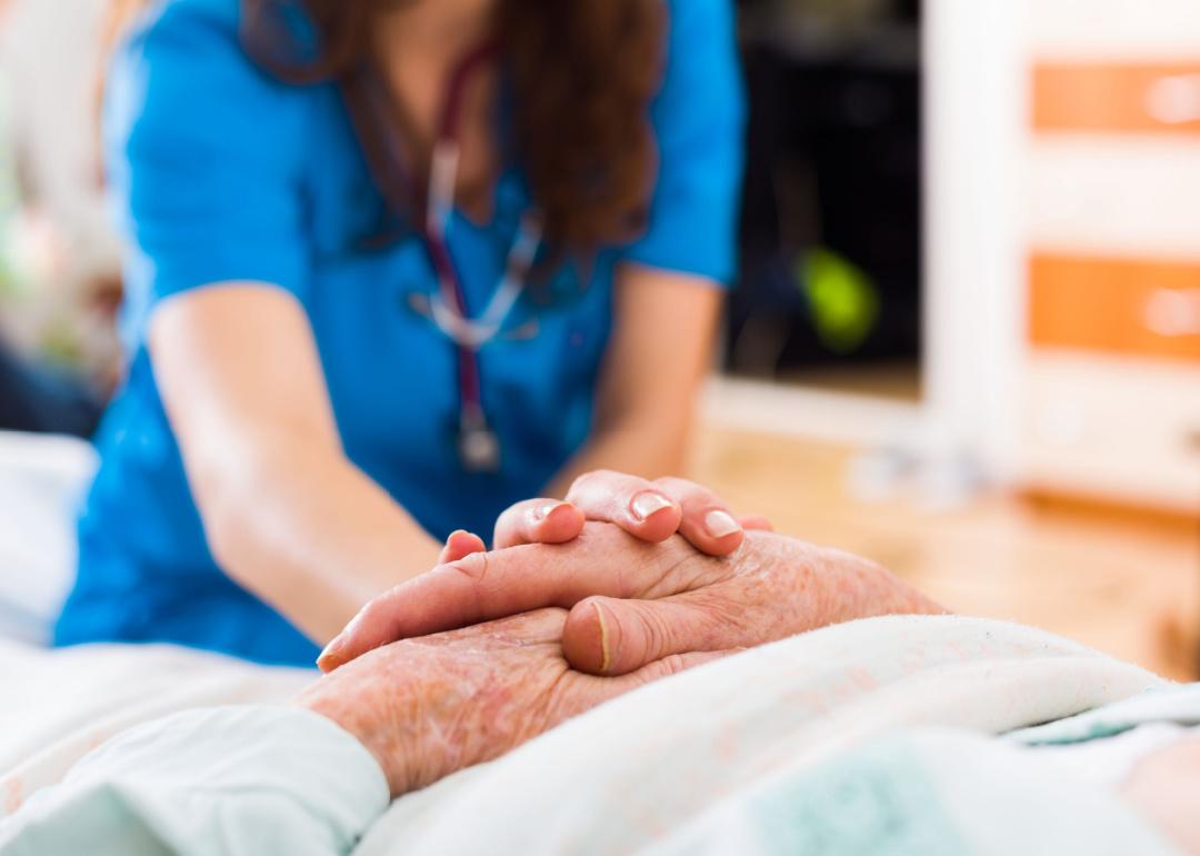 Closeup of hands of a senior stroke patient getting support from a medical professional.