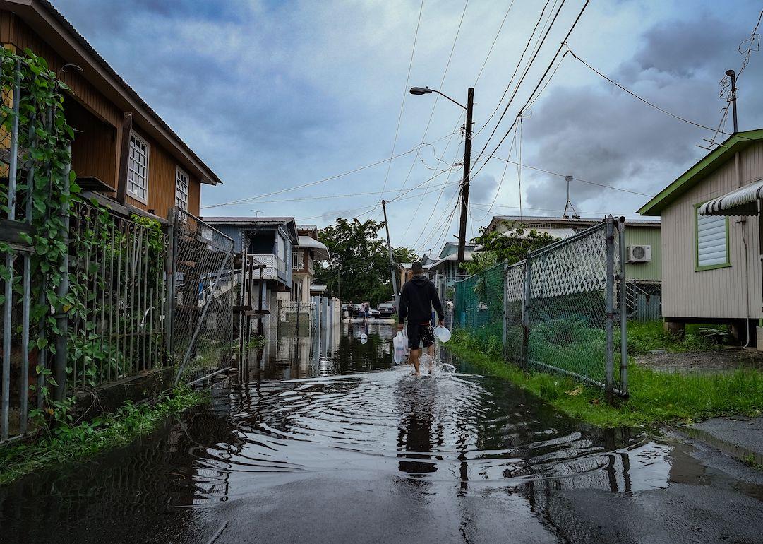 A man walks down a flooded street in the Juana Matos neighborhood of Catano, Puerto Rico, on September 19, 2022, after the passage of Hurricane Fiona.