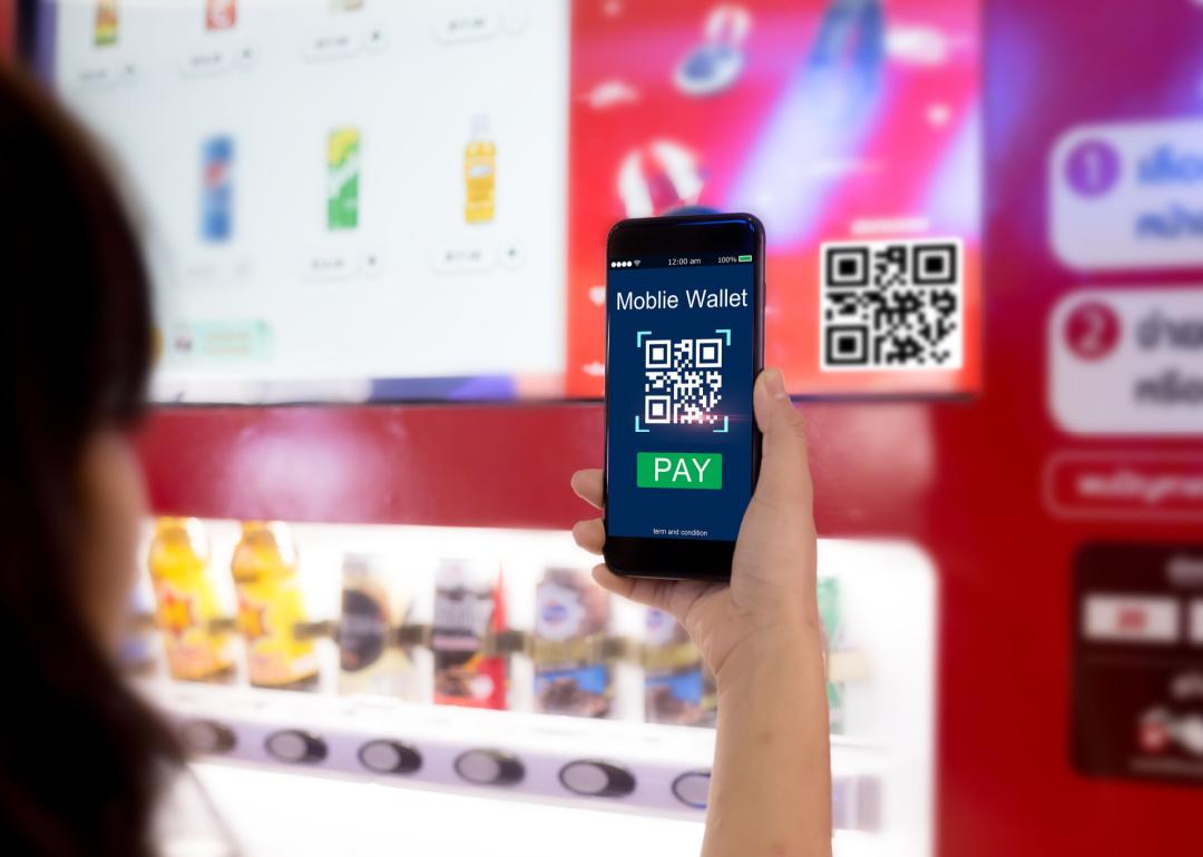 Closeup of person scanning a QR code via their mobile phone to pay for an item in a smart vending machine.