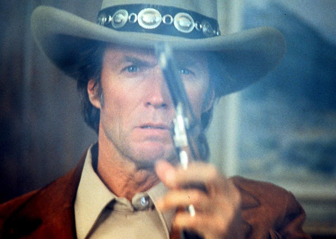 Clint Eastwood wearing a cowboy hat and holding a pointed gun in a scene from the film 'Bronco Billy', 1980.