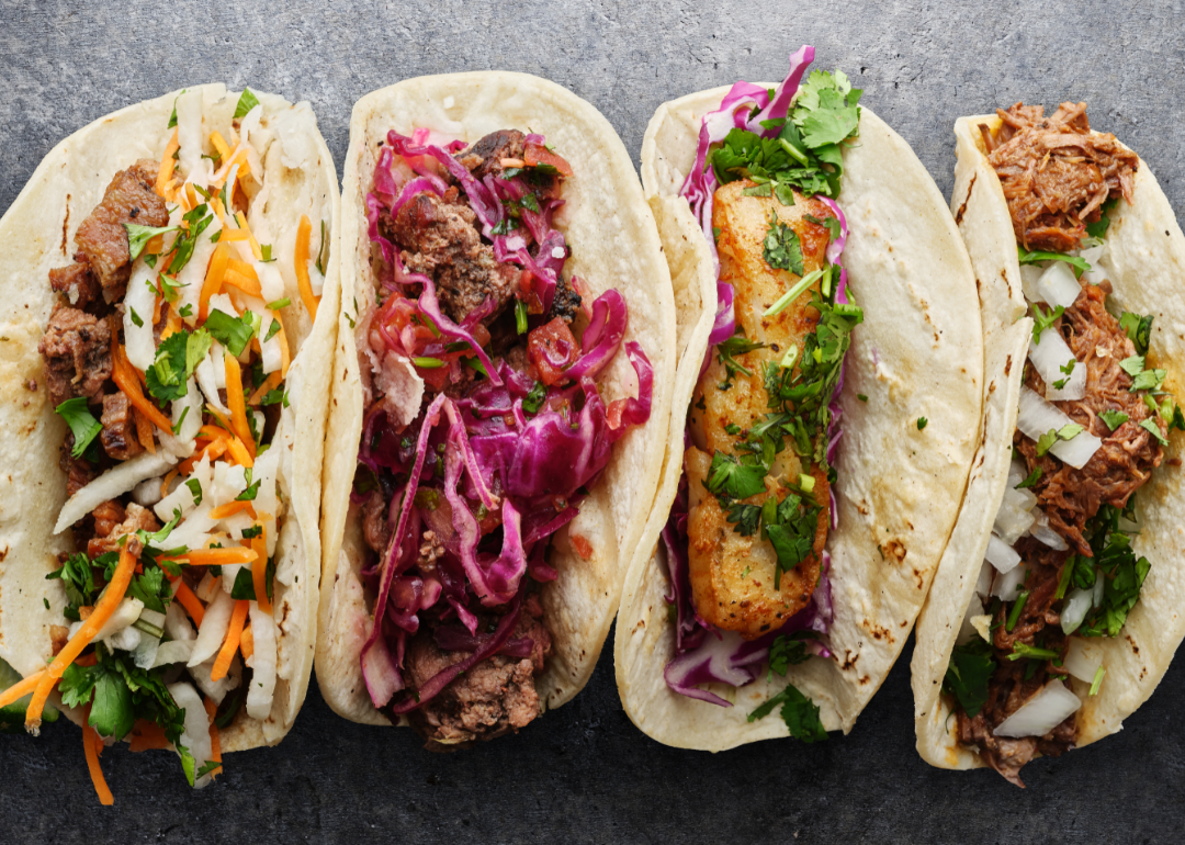 Four different Mexican street tacos on a gray background