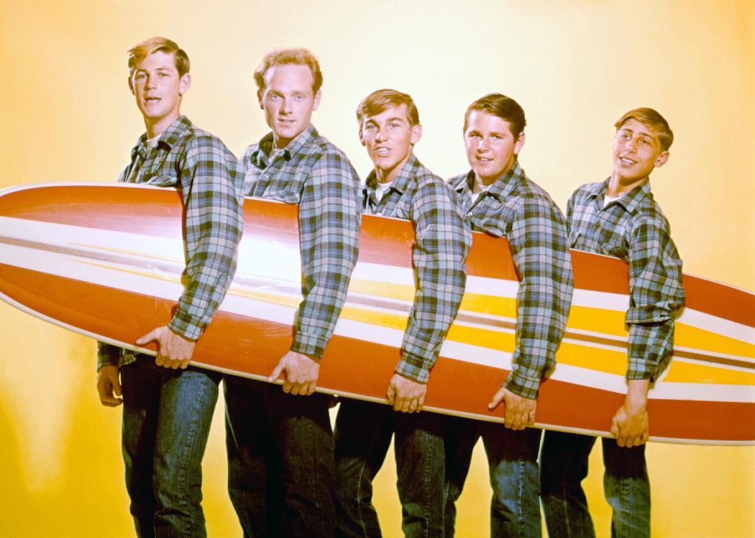 Rock and roll band "The Beach Boys" pose for a portrait with a surfboard in August 1962 in Los Angeles, California, from left: Brian Wilson, Mike Love, Dennis Wilson, Carl Wilson, David Marks.
