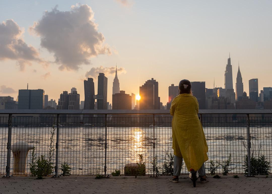 A woman watches the sunset the day after air quality was deemed 'unhealthy' due to wildfire smoke arriving from the west at Gantry Plaza State Park in Long Island City on July 21, 2021 in the Queens Borough of New York City.