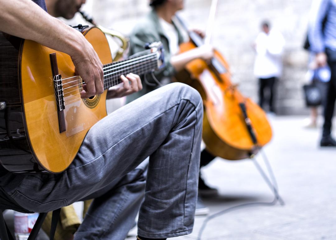 Closeup of street performers with a guitar and a cello playing for an audience.
