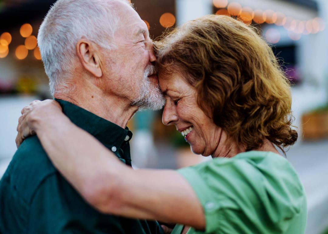 Senior couple dancing together in a garden outside.