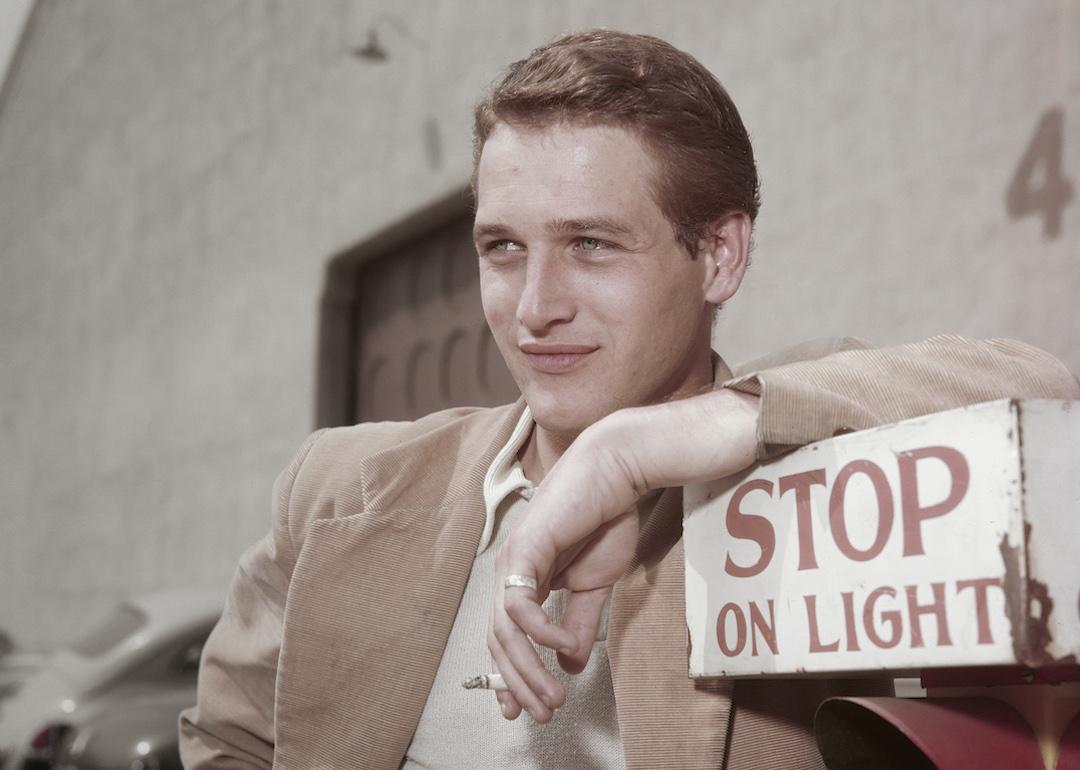 Paul Newman leaning on a sign which reads 'Stop on Light' at a film studio during the filming of 'The Silver Chalice', circa 1954.