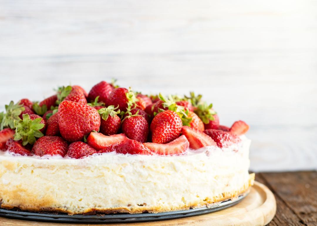 Low-sugar strawberry cheesecake with coconut on a wooden serving plate.