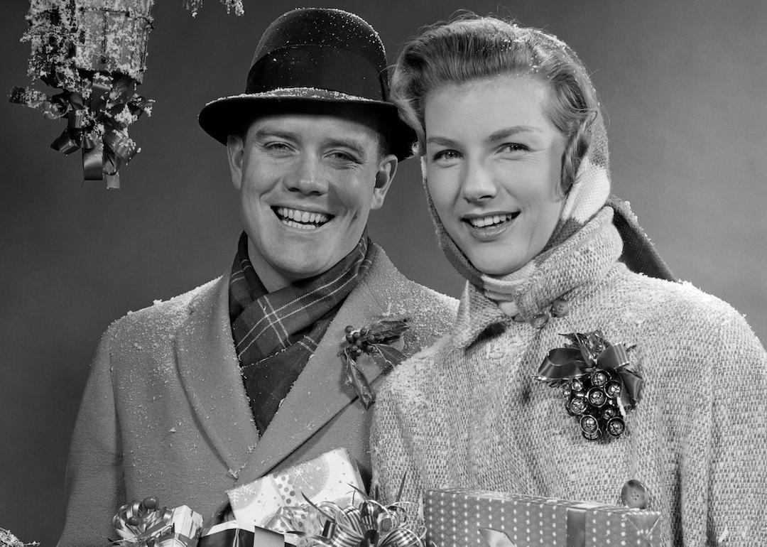 Couple wearing winter coats and carrying Christmas packages in the 1950s.