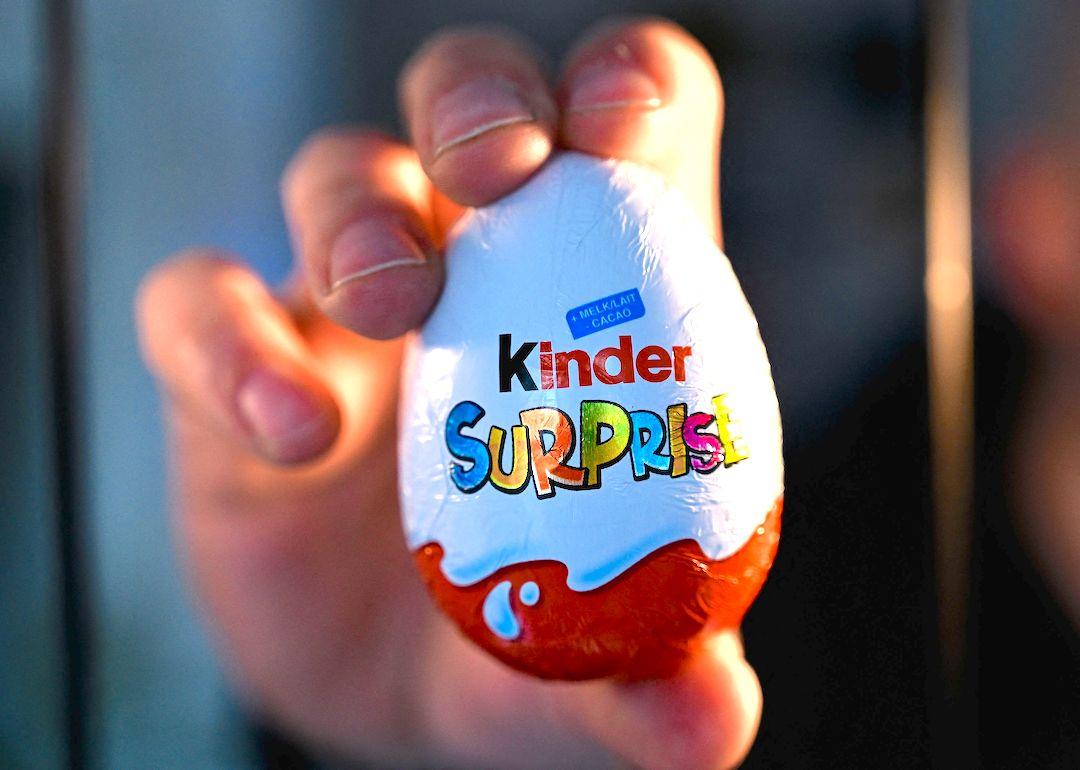 Hand holding 'Kinder Surprise' chocolate egg.