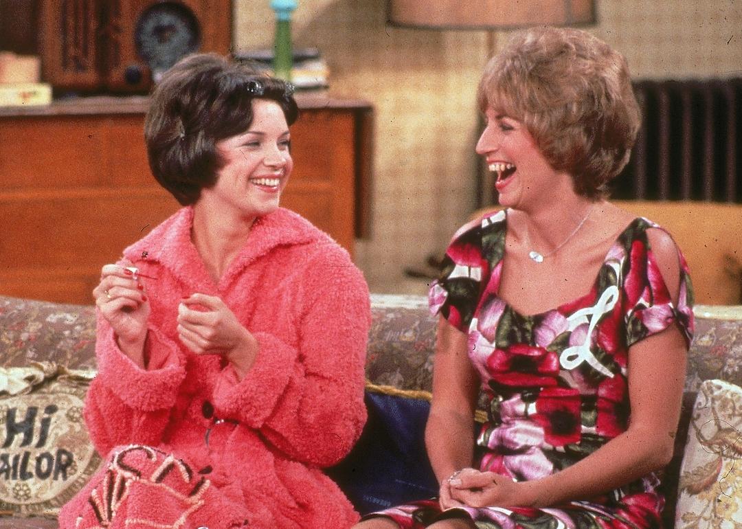 Actors Cindy Williams (left) and Penny Marshall (right) sit on the sofa laughing in a scene from 'Laverne and Shirley.'
