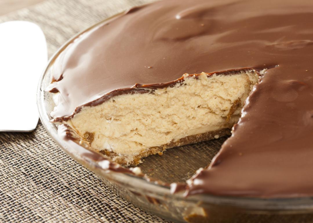 Peanut butter pie in a glass dish with a slice removed sitting on a table. 