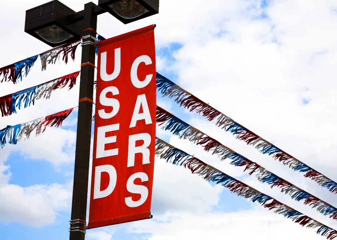 A Used Cars sign blows in the wind above a car lot.