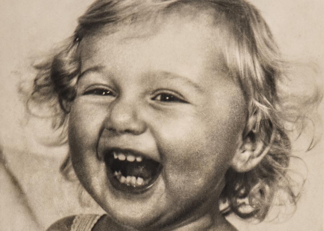 Vintage photo of baby smiling with curly light-colored hair.