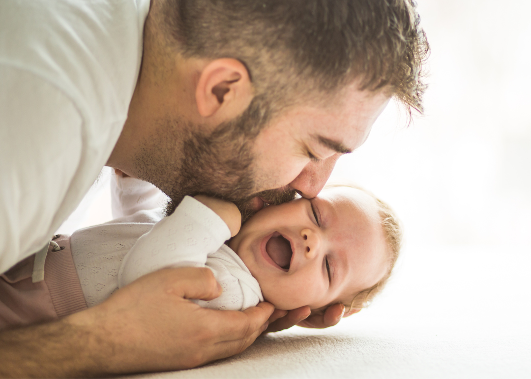 Parent kisses smiling newborn baby.